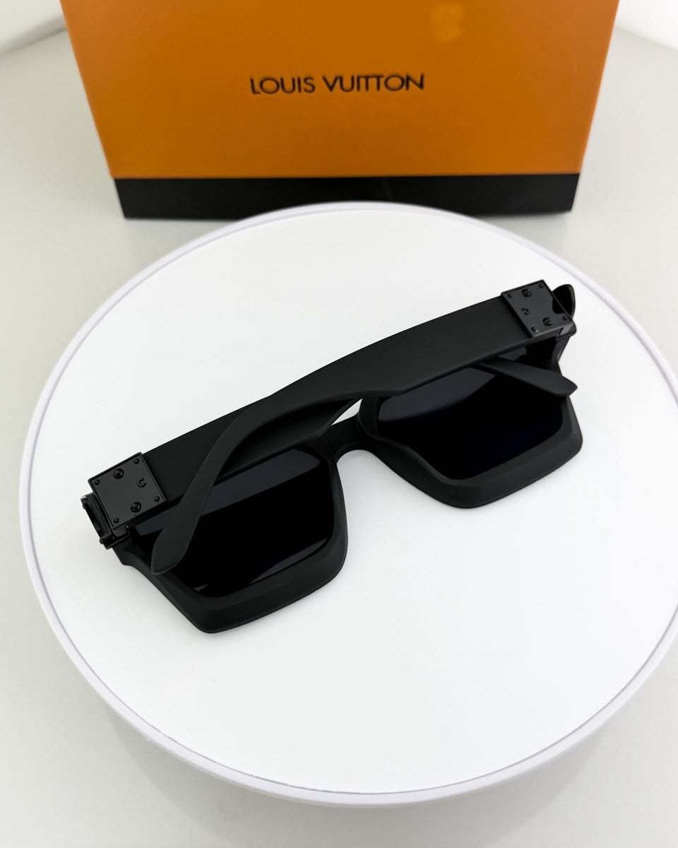 Black sunglasses on a white surface with a Louis Vuitton box in the background