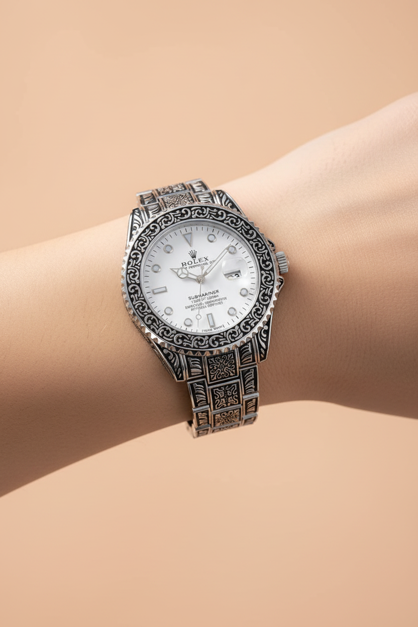 Engraved silver watch on wrist showing ornate pattern